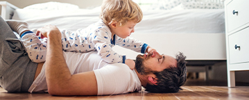 father and child playing on the bedroom hardwood floor